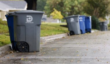 Recycling and garbage cans sit along a street in East Dallas in October 2022.