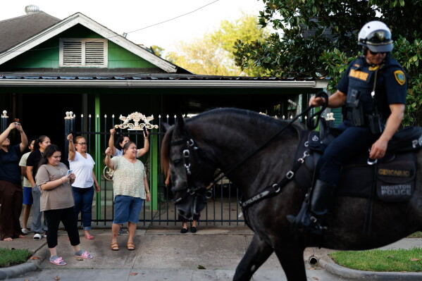 Neighbors cheer as marchers walk past during a vigil for Lorenzo Salgado Araujo, a Mexican national fatally shot by a federal immigration agent a day prior, Wednesday, July 8, 2026, in Houston. (AP Photo/Mark Felix)
