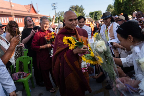 Bhikkhu Pannakara, a Buddhist monk who led a Walk for Peace from Fort Worth, Texas, to Washington, D.C., receives flowers from well-wishers during an event at Wat Thai of Los Angeles in the North Hollywood section of Los Angeles, Monday, July 13, 2026. (AP Photo/Jae C. Hong)