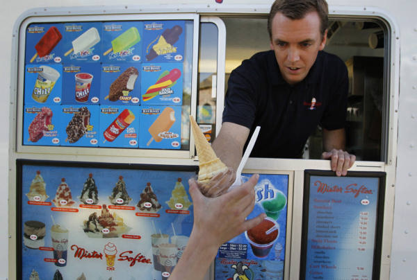 Patrick Haile with his Mr. Softee ice cream truck hands off a chocolate cone to a customer in Southlake.