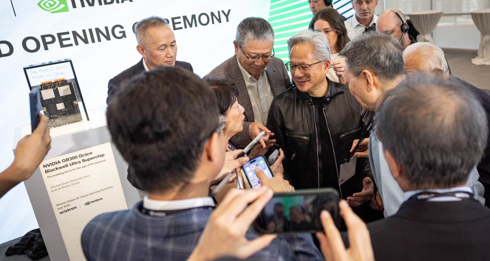 Wistron Chairman Simon Lin lifts his glasses to read a transcription on a gift to Nvidia founder and CEO Jensen Huang at an opening ceremony of a new state-of-the-art Wistron manufacturing facility that will assemble and test Nvidia AI systems in Fort Worth on Tuesday, July 21, 2026.