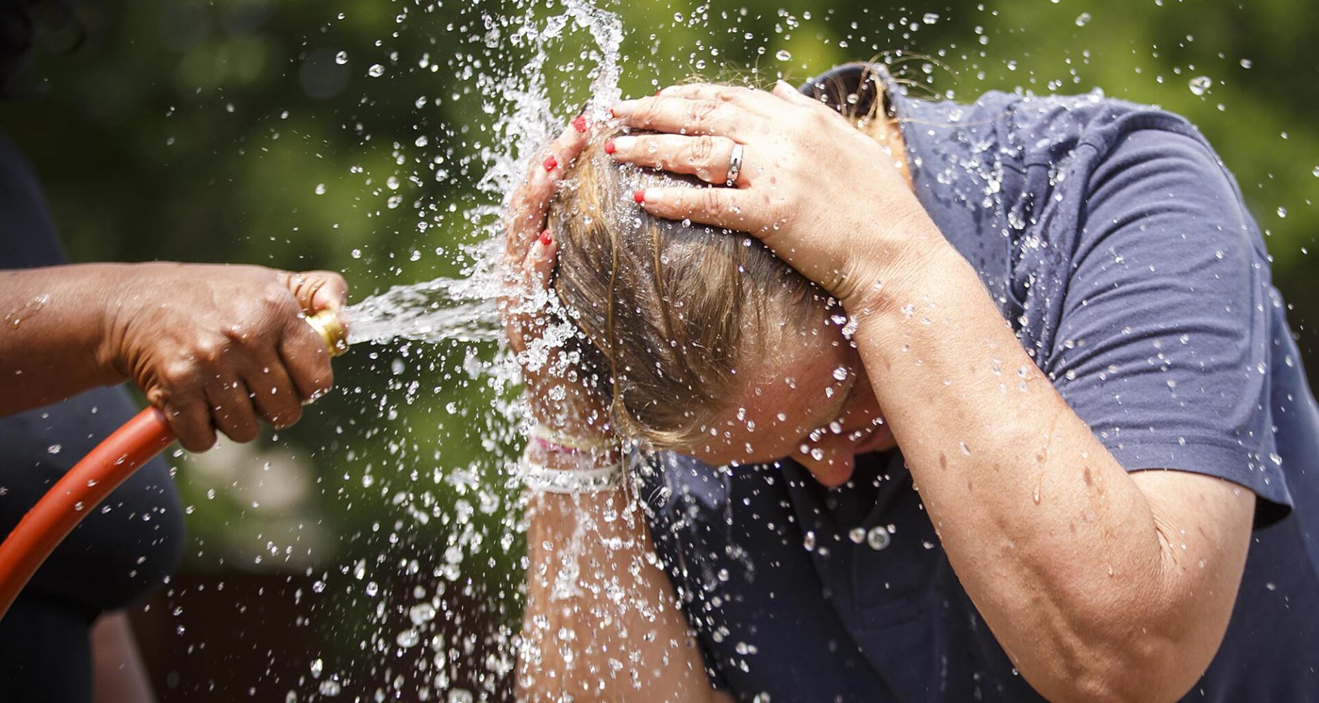 Rochelle Austin cools off in the spray from a watering hose while she works in the New Hope Garden at the Austin Street Center on Tuesday, May 30, 2017, in Dallas.