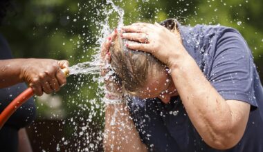 Rochelle Austin cools off in the spray from a watering hose while she works in the New Hope Garden at the Austin Street Center on Tuesday, May 30, 2017, in Dallas.