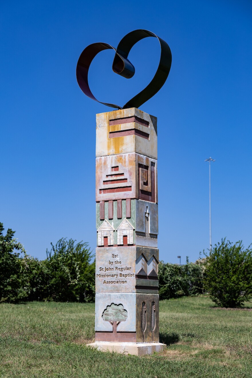 A vertical sculpture features a heart shaped piece at the top. Each block has its own art piece and color honoring the St. John Regular Baptist District Association.