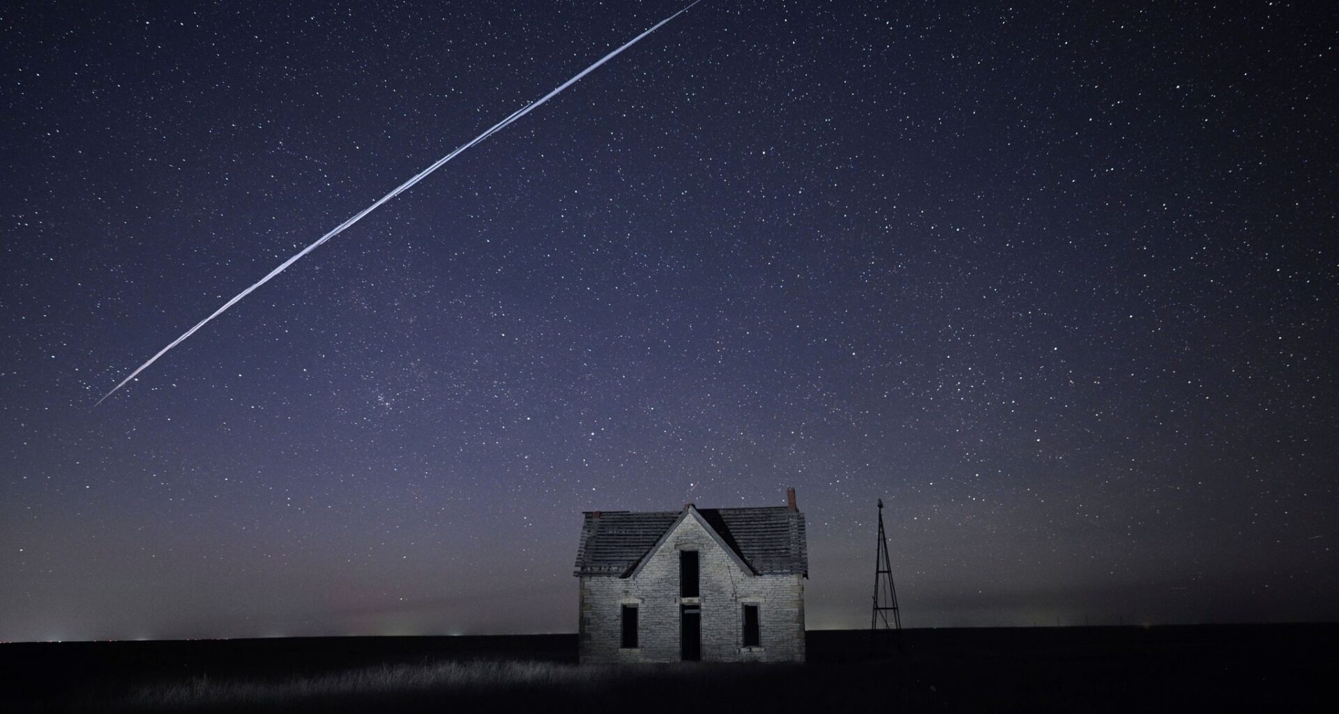 FILE - In this long exposure photo, a string of SpaceX StarLink satellites passes over an old stone house near Florence, Kan., on May 6, 2021. (AP Photo/Reed Hoffmann, File)