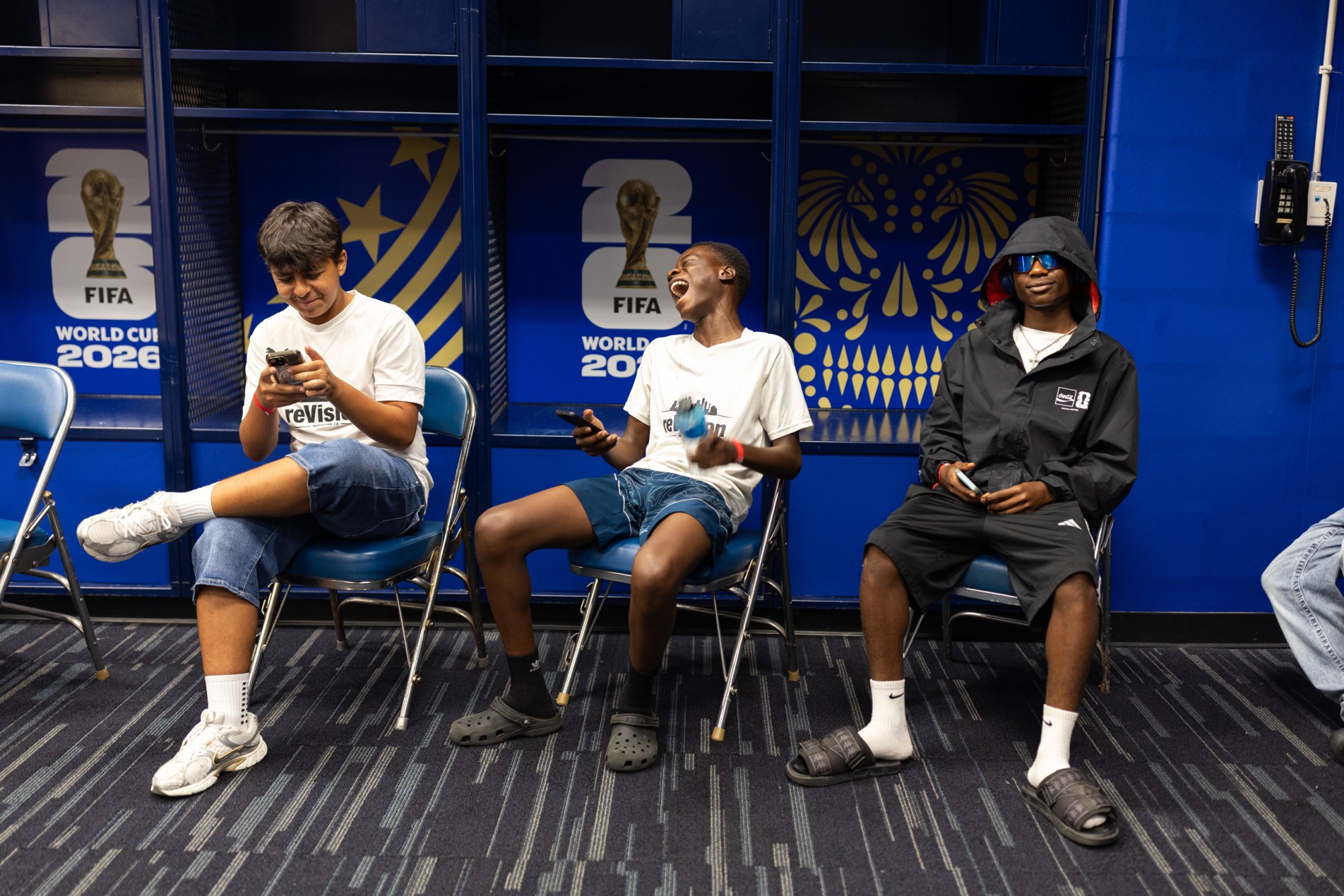 Arian Yousofi, Kenasi Mwami and Moises Badera, left to right, laugh as they sit in the locker room used by the Moroccan national team days earlier in their World Cup match, in early July.