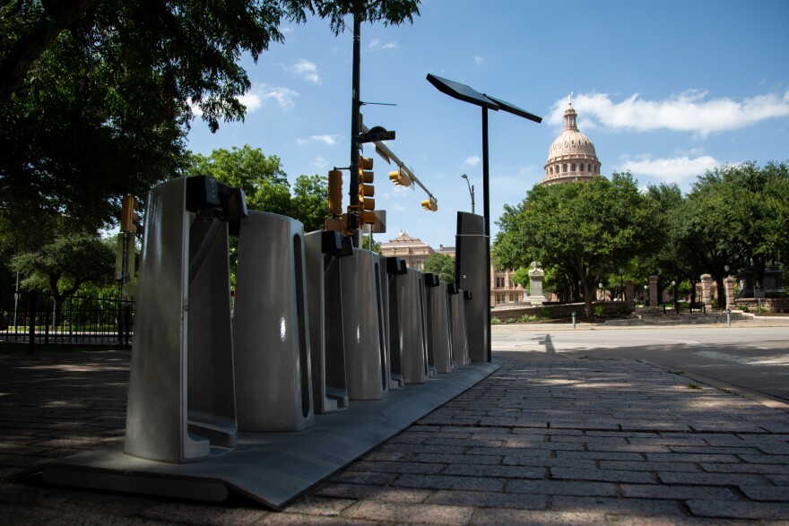 An empty CapMetro Bikeshare station is pictured on the corner of 11th Street and Congress Ave on Tuesday, June 23, 2026. The Texas Capitol dome is pictured in the background.