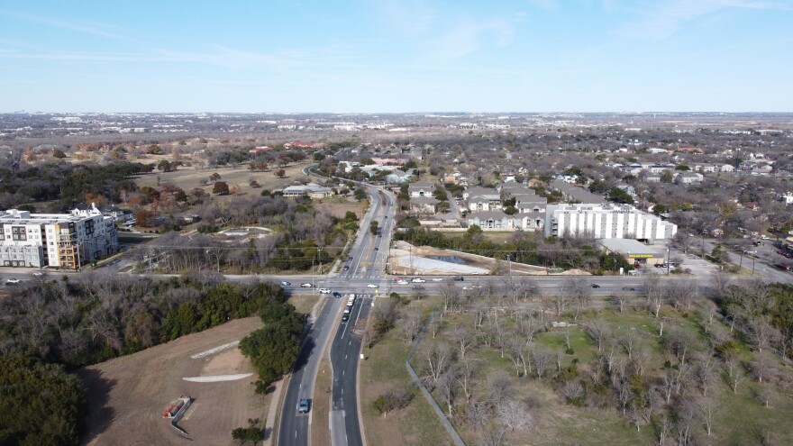 An aerial view of land around the intersection of Riverside Drive and Grove Boulevard. Some apartment buildings are visible north of Riverside. South of Riverside, it appears to me mostly vacant land except for trees and bushes.