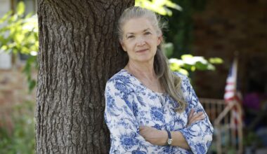 Grace Barber, 65, a retired nurse and teacher, poses for a photo in front of the house where she lives with her daughter, Wednesday, July 22, 2026, in Dallas.