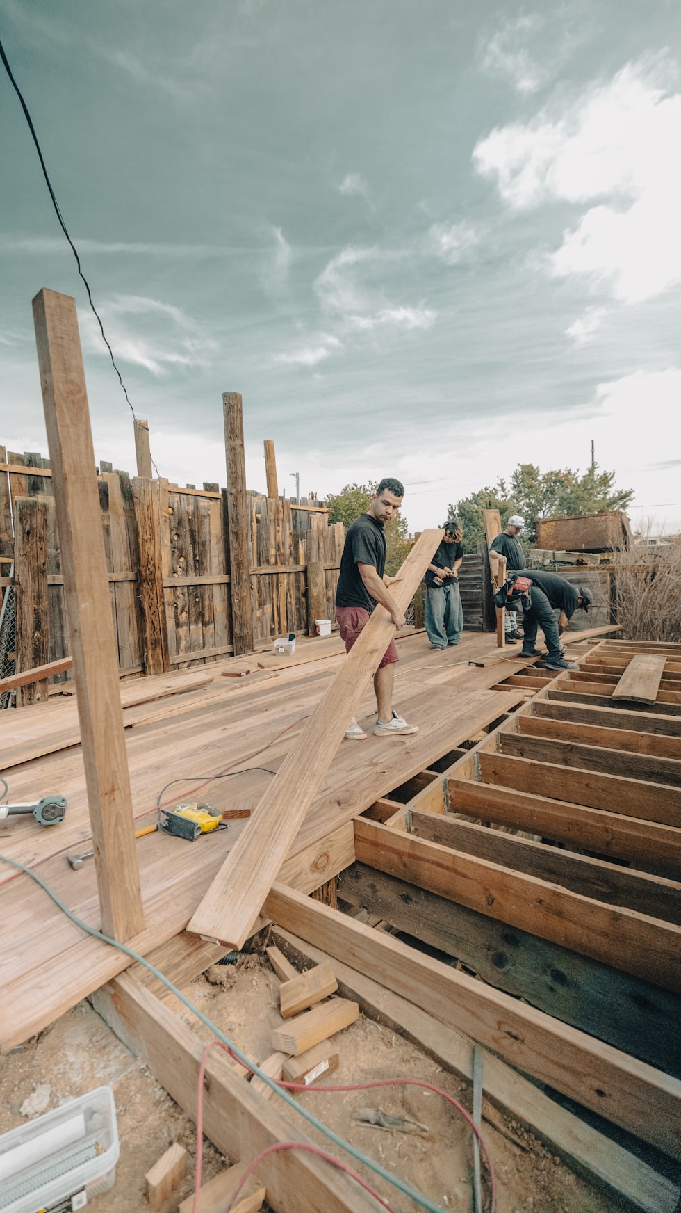 Construction workers building a wooden deck outdoors.