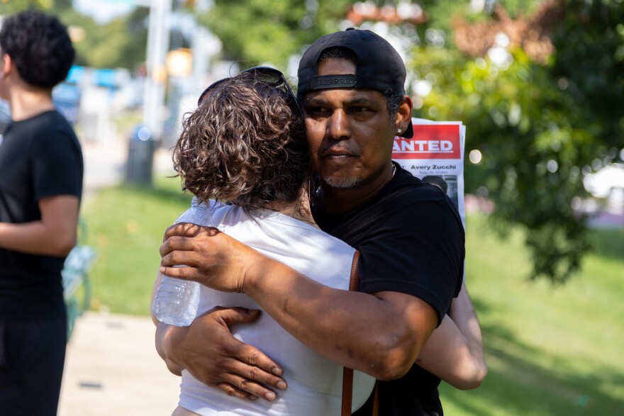 A man hugs another person outside.