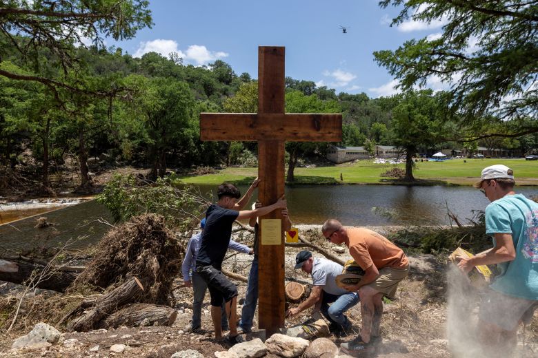 People place a cross by the Guadalupe River, across from Camp Mystic, following deadly flooding, in Hunt, Texas, on July 10, 2025.