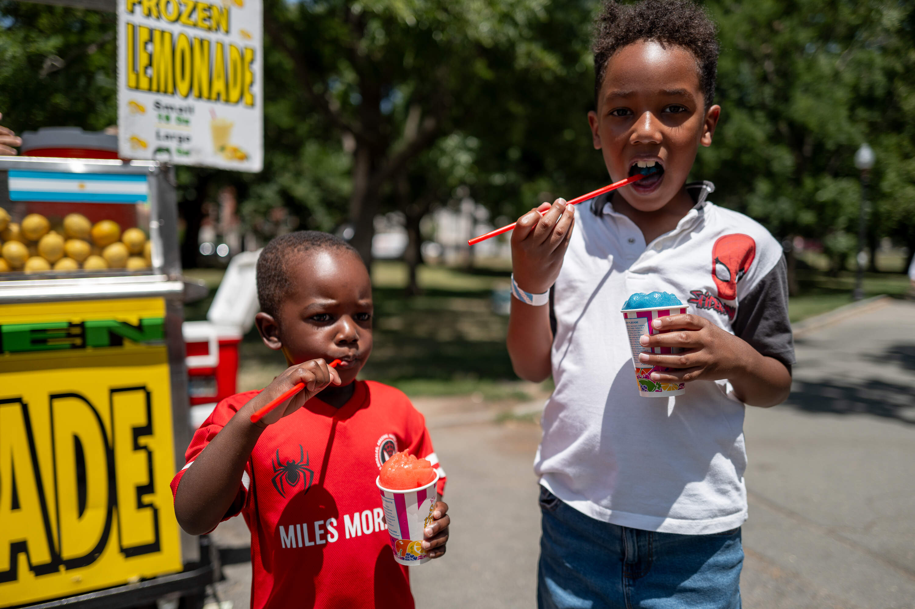 Siblings Clarence Kisambira and Christian Diaz of Brookline eat Italian ice from a food stand in Boston Common. (Artemisia Luk/WBUR)