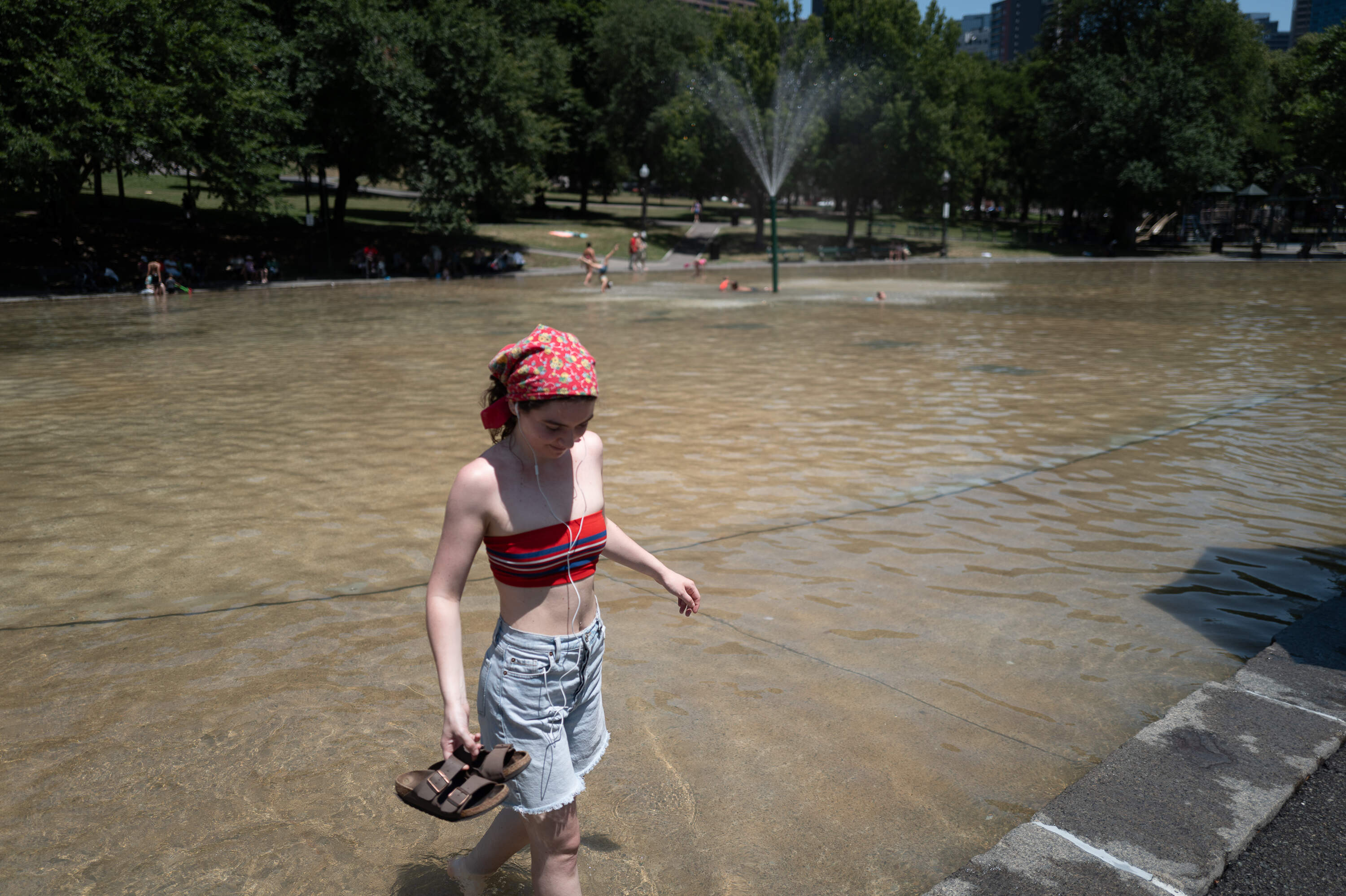 Madeline Matonti cools off during her off-work hours by taking a barefoot stroll through Frog Pond. She says that her apartment in Beacon Hill doesn’t have central air conditioning. (Artemisia Luk/WBUR)