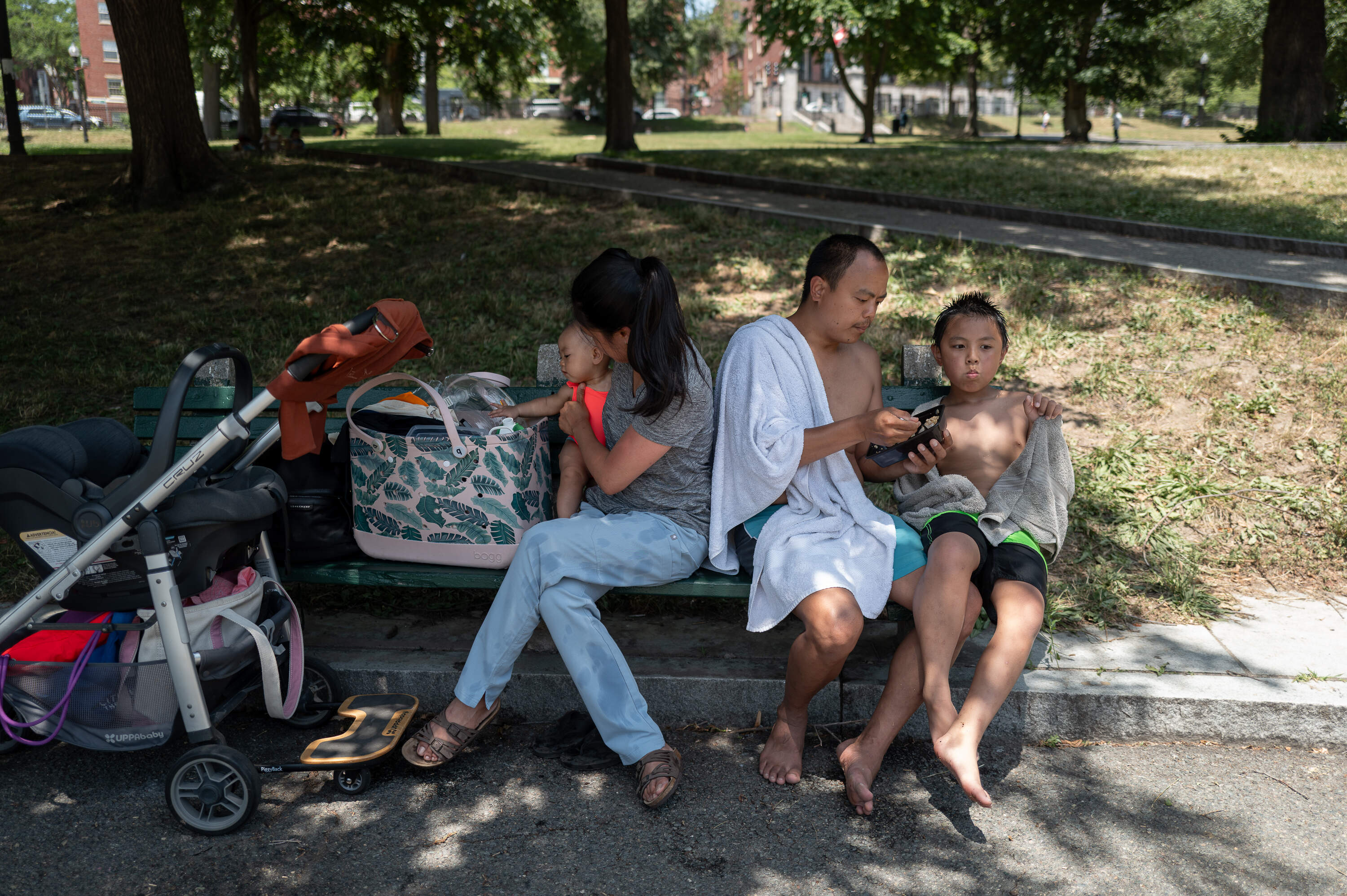 Isabella Lim, Irene Lim, Aldrica Lim and Adrian Lim of Canton sit on a shady bench in Boston Common. They’re grateful for the free local recreational facilities like Frog Pond, which Aldrica Lim says was less common in the Philippines, where the family is from. (Artemisia Luk/WBUR)
