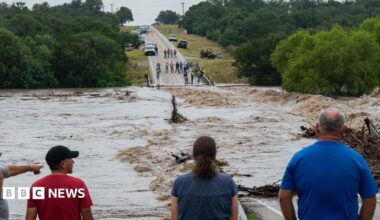 A group of people observe a flooded road
