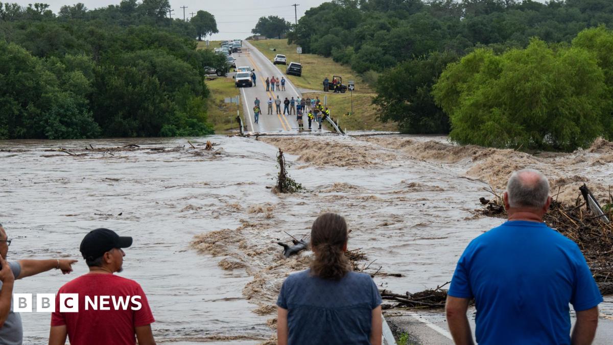 A group of people observe a flooded road