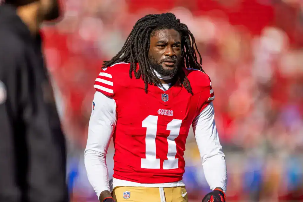 Brandon Aiyuk stands on the field in his red San Francisco 49ers No. 11 uniform.
