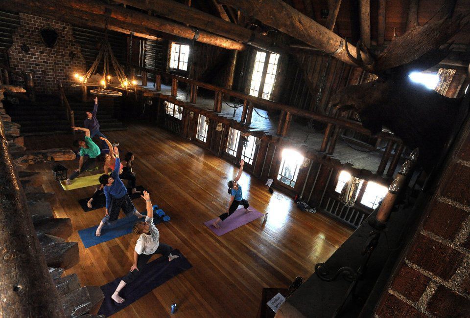 Six people posing on yoga mats insdie a large wooden cabin