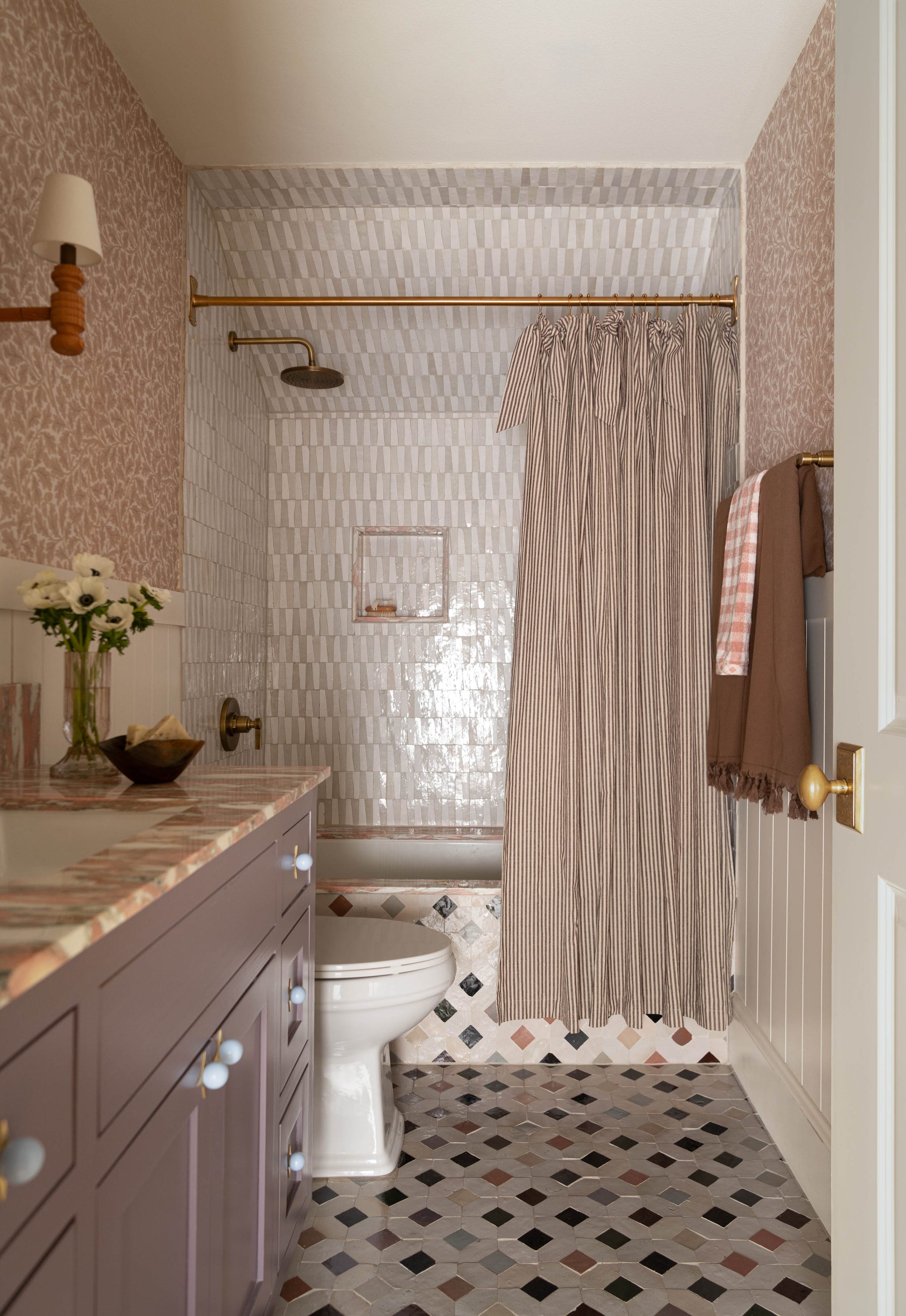 Modern bathroom featuring a shower area, patterned tiles, and a floral vase on the countertop.