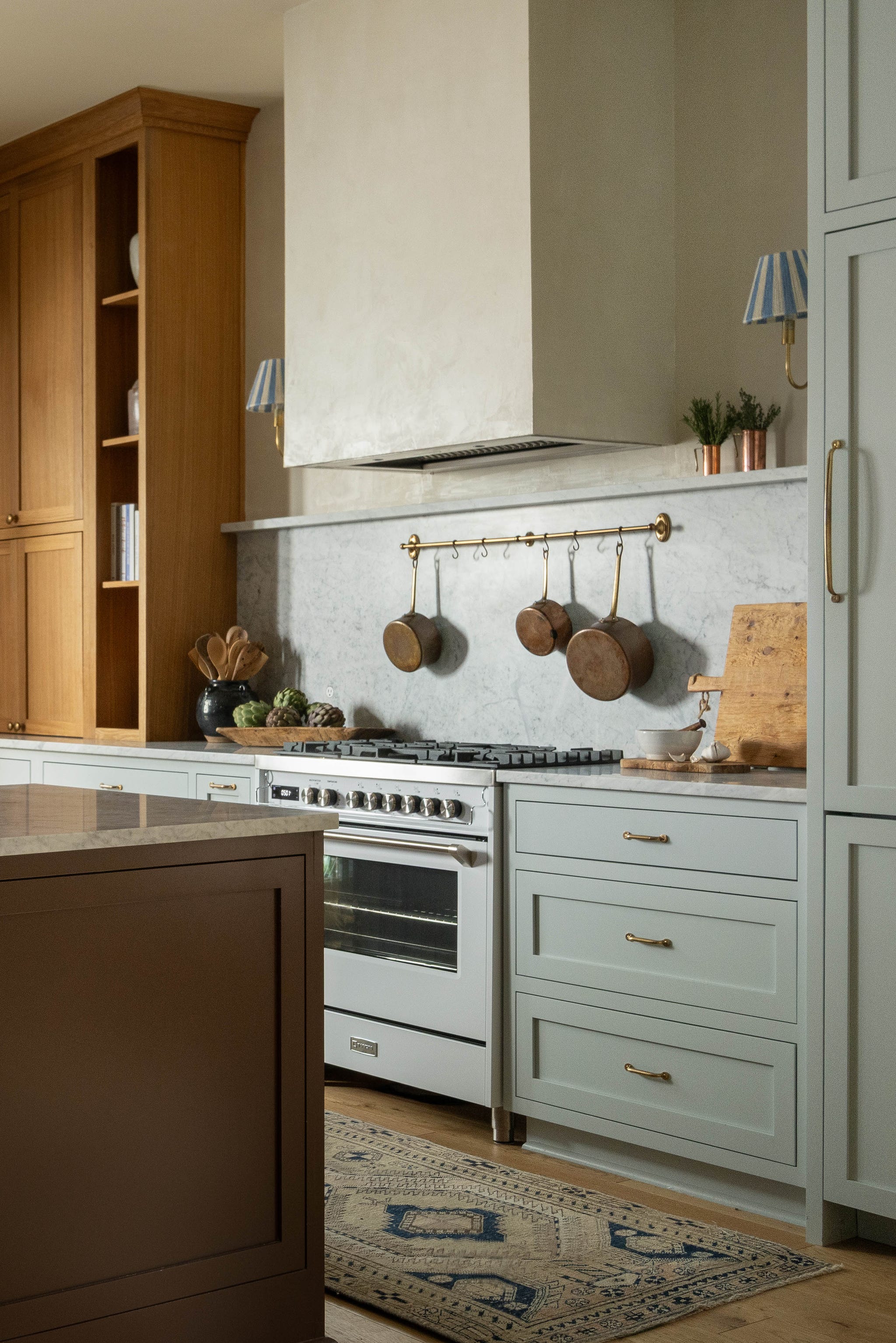 Modern kitchen interior featuring light cabinetry, marble backsplash, hanging pots, and a central island. Modern kitchen interior featuring light cabinetry, marble backsplash, hanging pots, and a central island.