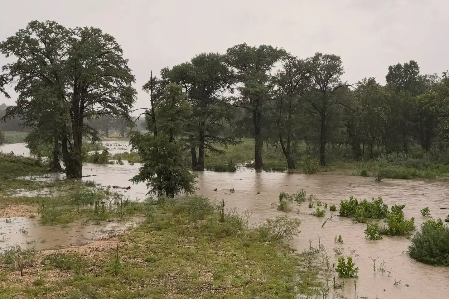 Floodwaters cover low-lying land near Comfort on July 15, 2026, after days of heavy rain raised waterways across the Texas Hill Country.