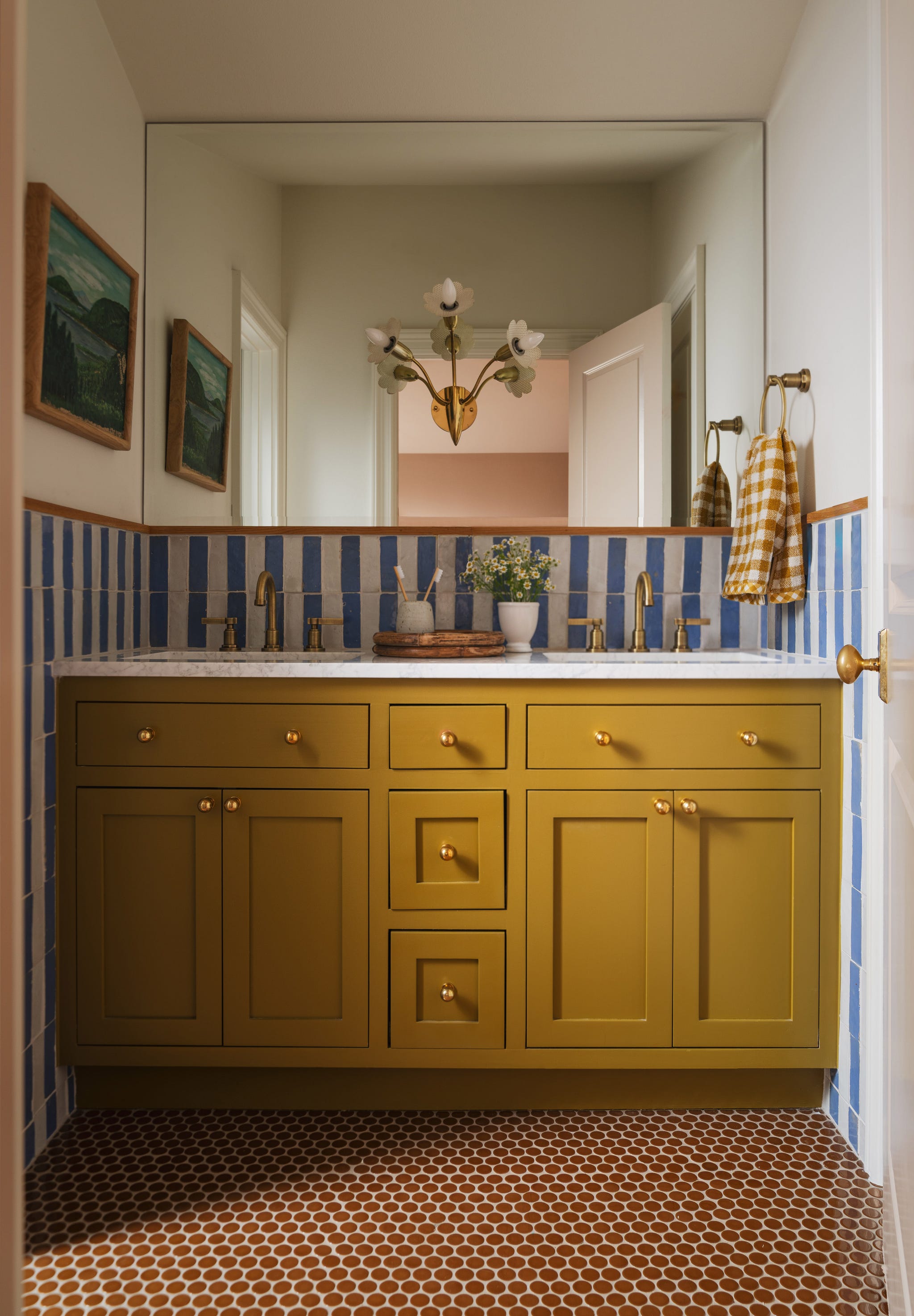 A stylish bathroom featuring yellow cabinetry, blue tiled walls, and hexagonal patterned flooring.