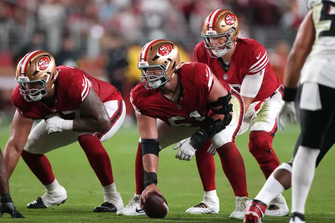Oct 19, 2025; Santa Clara, California, USA; San Francisco 49ers center Matt Hennessy (center) prepares to snap the ball to quarterback Mac Jones (center right) during the fourth quarter against the Atlanta Falcons at Levi's Stadium. Mandatory Credit: Darren Yamashita-Imagn Images