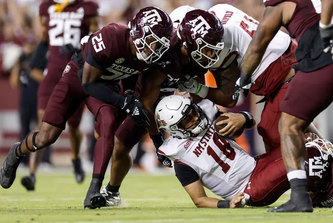 COLLEGE STATION, TEXAS - NOVEMBER 16: Santino Marucci #18 of the New Mexico State Aggies is tackled by Daymion Sanford #27 of the Texas A & M Aggies and Dalton Brooks #25 in the second quarter at Kyle Field on November 16, 2024 in College Station, Texas. (Photo by Tim Warner/Getty Images)