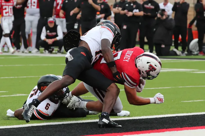 Oct 25, 2025; Lubbock, Texas, USA; Texas Tech Red Raiders running back Cameron Dickey (8) scores against Oklahoma State Cowboys defensive back Eric Fletcher (13) and defensive back Brandon Rawls (6) in the first half at Jones AT & T Stadium. Mandatory Credit: Michael C. Johnson-Imagn Images