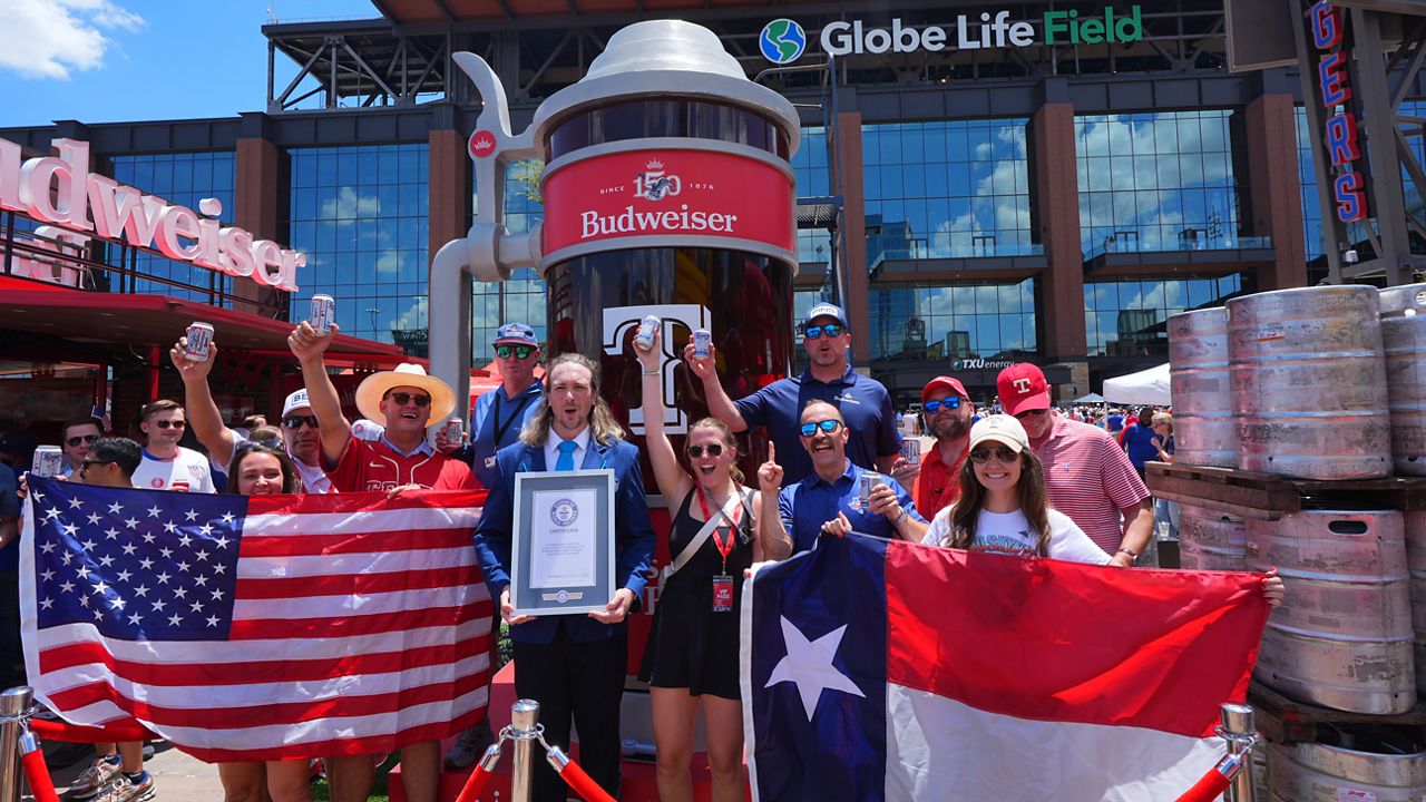 Guinness World Records adjudicator Thomas Bradford, center, cheers with others aftercertifying a world record for Largest Glass of Beer ahead of a baseball game between the Detroit Tigers and Texas Rangers, Saturday, July 4, 2026, in Arlington, Texas. (AP Photo/LM Otero)