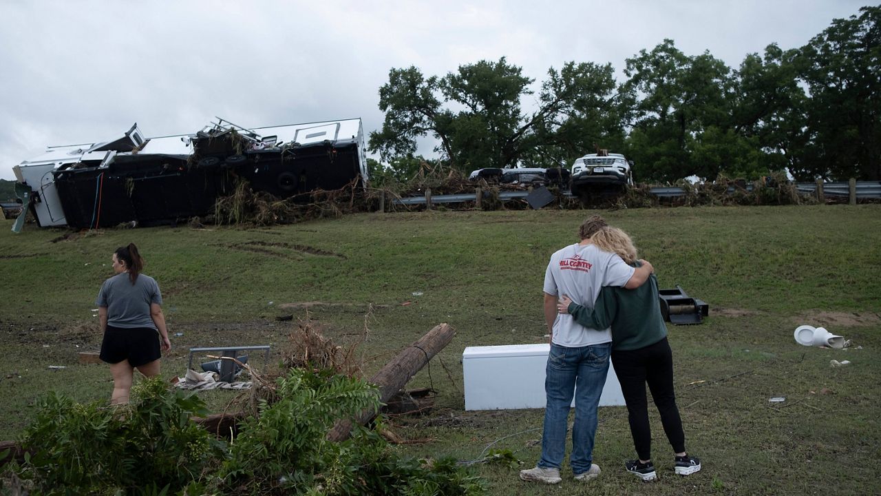 Ryder Wade is comforted by his mother Crystal Wade as they assess flood debris and damage scattered across the Buckhorn Lake Resort RV Park following floods along West Goat Creek near the Guadalupe River on Friday, July 17, 2026, in Kerrville, Texas. (AP Photo/Joel Angel Juarez)