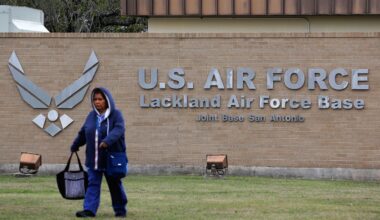 A pedestrian passes the main gate at Lackland Air Force Base in San Antonio, Wednesday, Feb. 5, 2020. (AP Photo/Eric Gay)