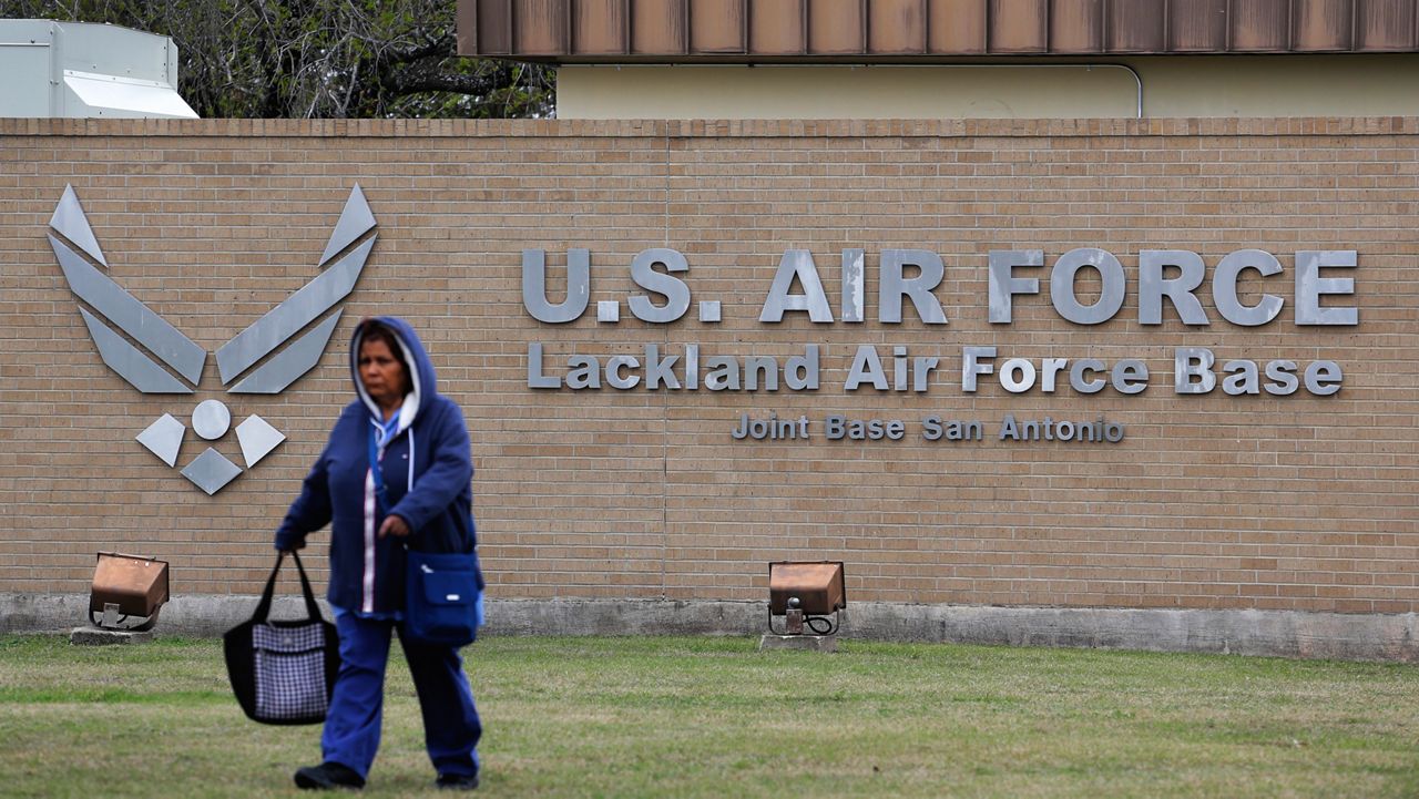 A pedestrian passes the main gate at Lackland Air Force Base in San Antonio, Wednesday, Feb. 5, 2020. (AP Photo/Eric Gay)