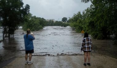 Mike Erulenfeld and Kala Martin watch as the Pedernales River floods near Old Kerr Highway on Thursday, July 16, 2026, in Fredericksburg, Texas. (AP Photo/Joel Angel Juarez)