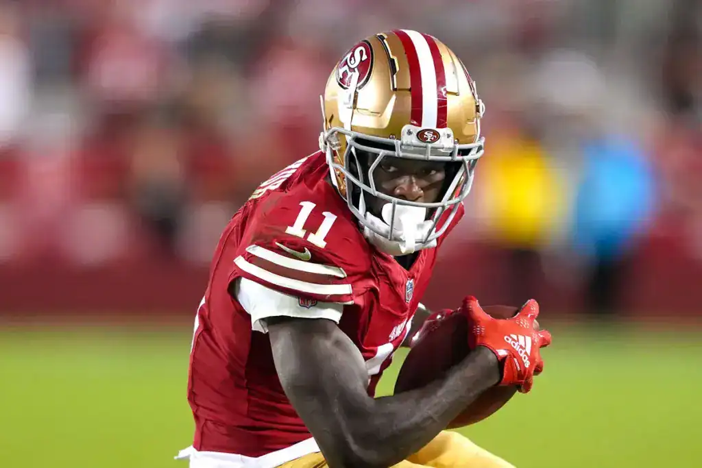 San Francisco 49ers wide receiver Brandon Aiyuk carries the football while looking upfield during a game.