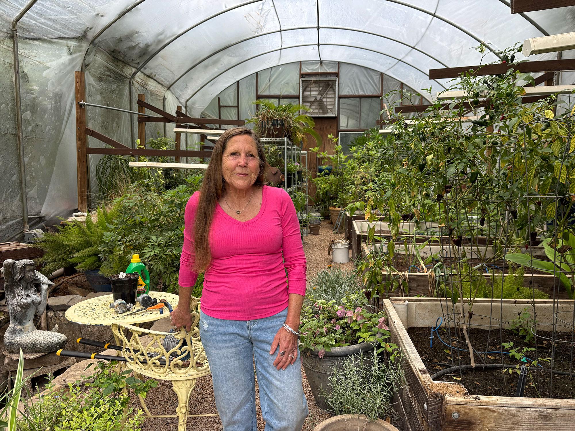 A woman stands in a greenhouse