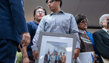 Lorenzo Salgado Araujo's son holds a photo of his family at a press conference the day after his father was fatally shot by an ICE agent.