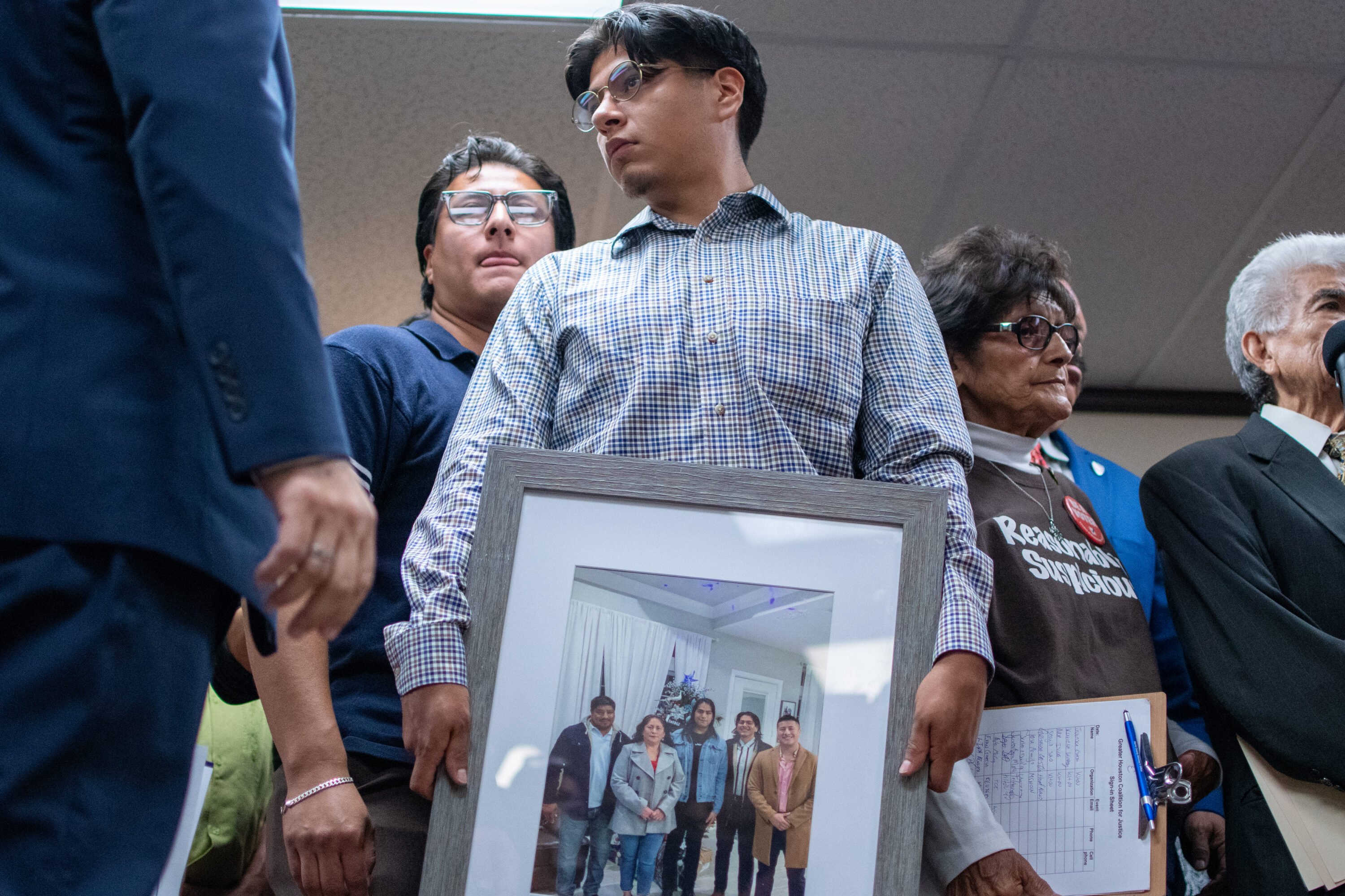 Lorenzo Salgado Araujo's son holds a photo of his family at a press conference the day after his father was fatally shot by an ICE agent.