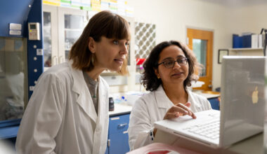 A photo of two women looking at a laptop computer in a research laboratory.