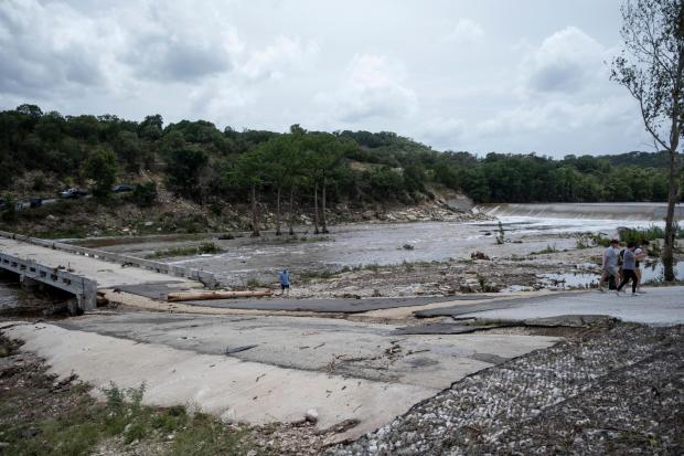 People walk along the Guadalupe River after heavy floods on Friday, July 17, 2026, in Ingram, Texas. (AP Photo/Joel Angel Juarez)