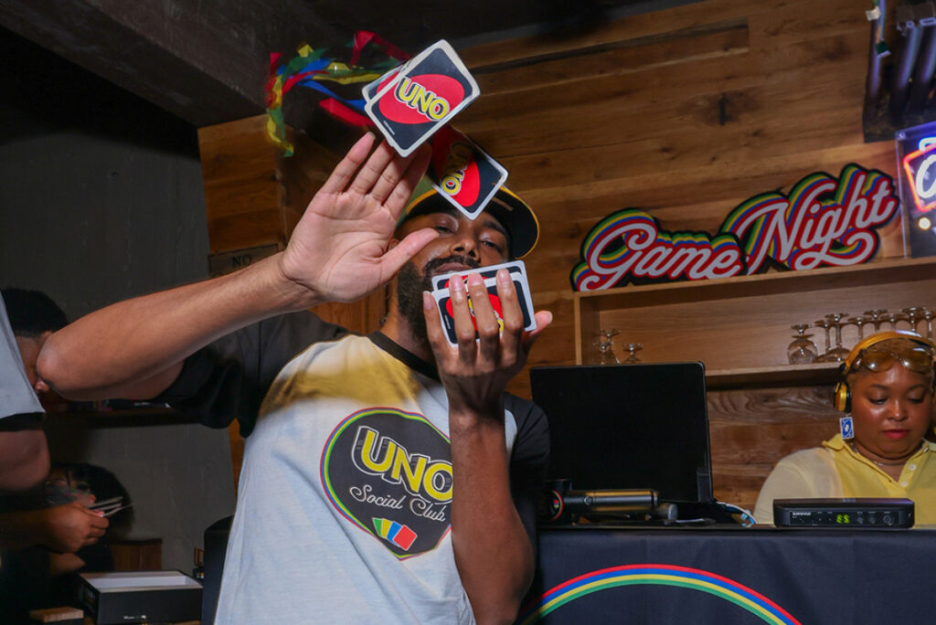 Image shows a man making it rain with UNO cards at a UNO Social Club pop-up.