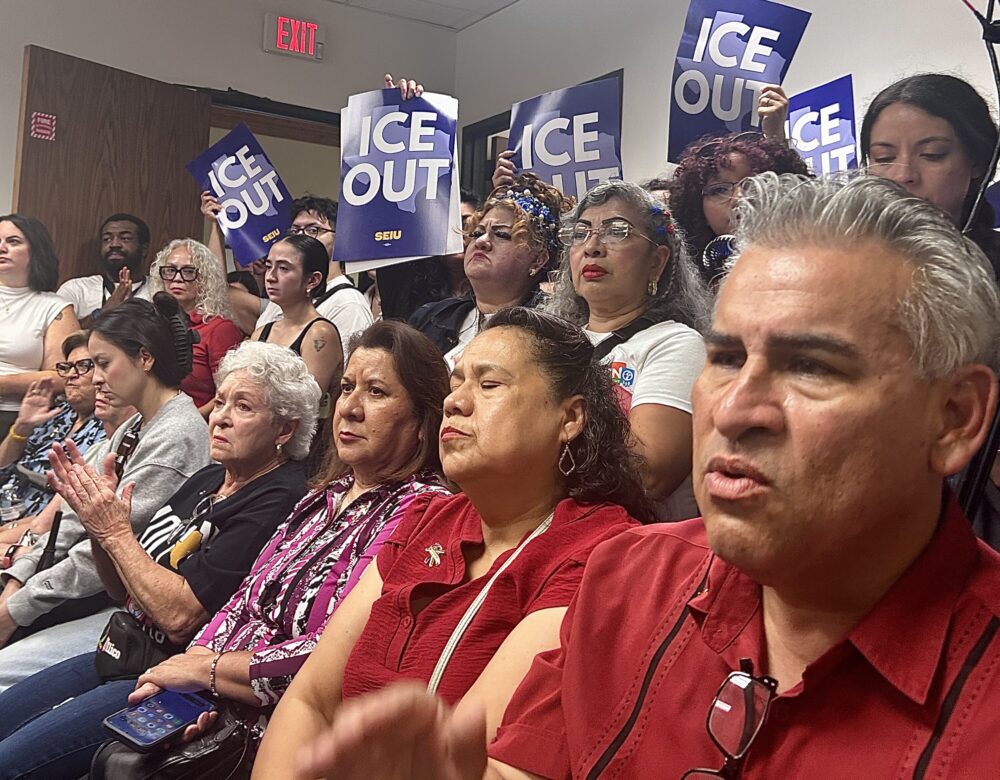 Attendees hold ICE OUT signs at the vigil for Lorenzo Salgado Araujo. Salgado Araujo was shot and killed during an ICE "targeted enforcement operation" on July 7.