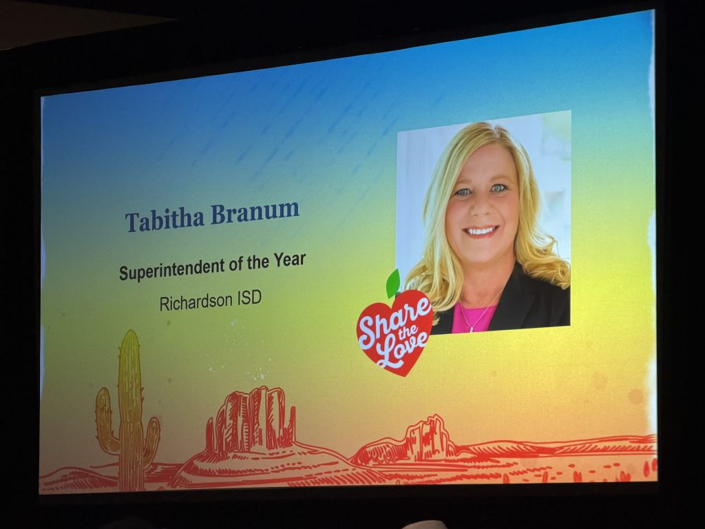 Photo of a screen with slide "Tabitha Branum - Superintendent of the Year - Richardson ISD" with her headshot and "Share the Love" logo.