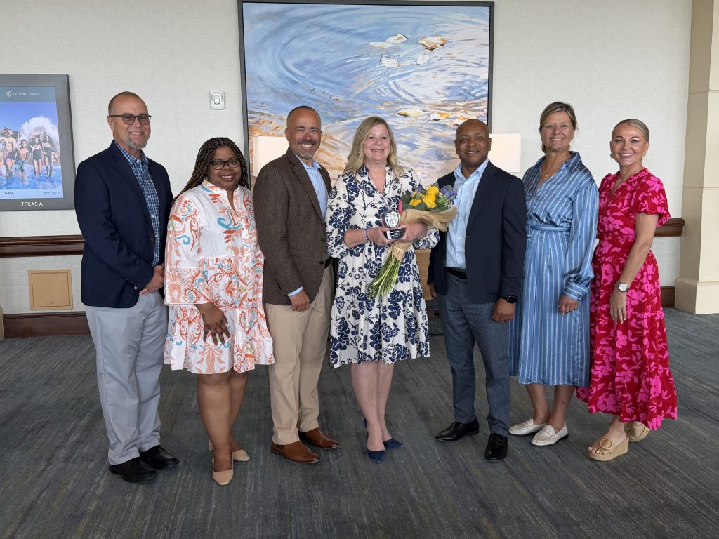Supeintendent with cabinet members holding award and flowers