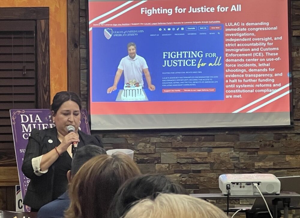 A power point displays a photo of Lorenzo Salgado Araujo and a woman stands in front with a microphone