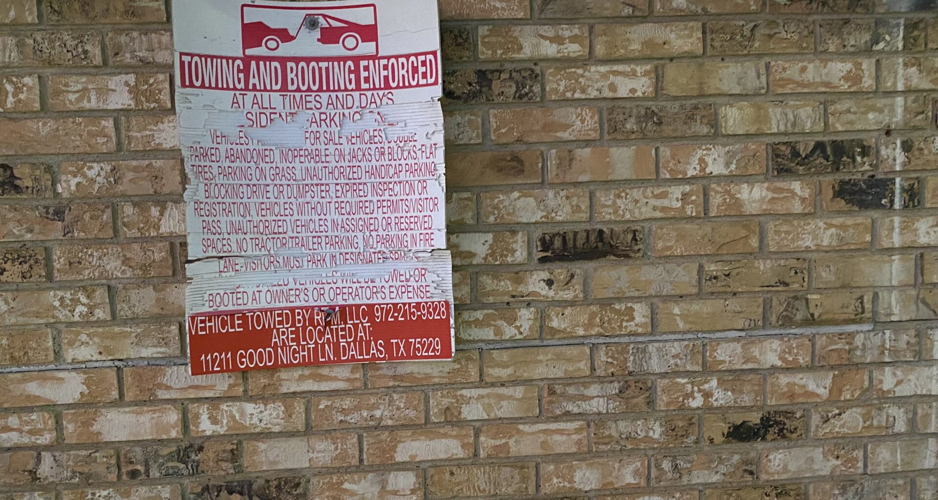 a tow-away sign on a brick wall.
