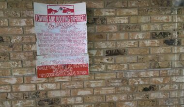a tow-away sign on a brick wall.