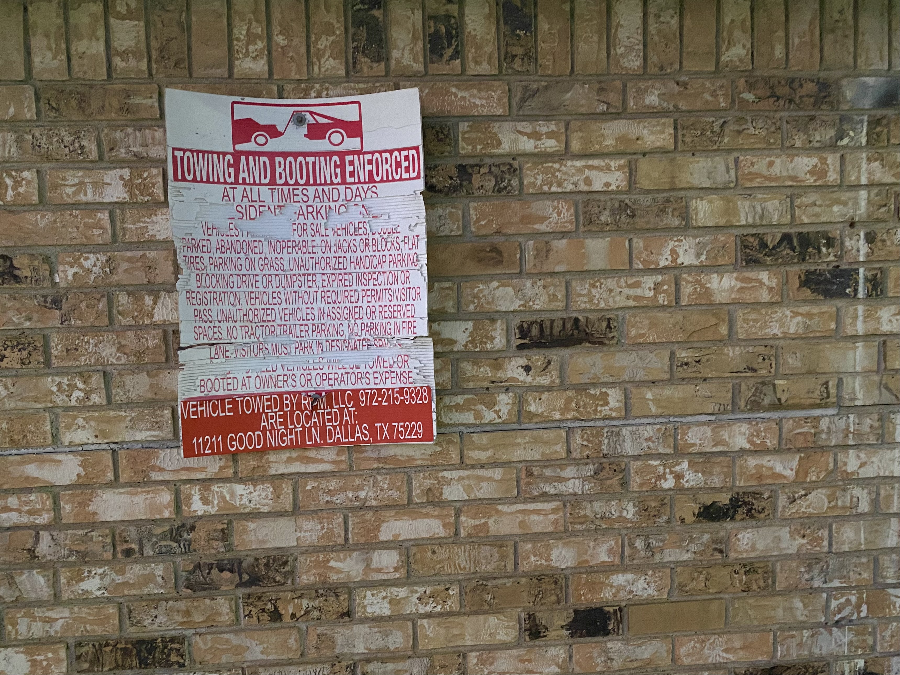 a tow-away sign on a brick wall.