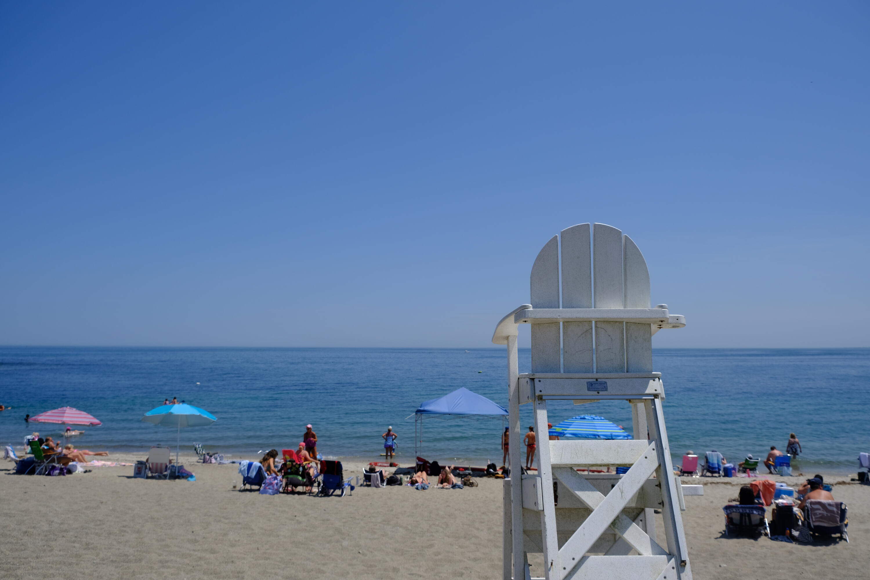 Beachgoers sit throughout Peggotty Beach in Scituate on July 2, 2026. (Patrick Madden/WBUR)